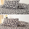 A set of leopard print decorative pillow covers in black and gray on a bed.