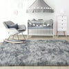 A plush gray long-pile area rug placed in front of a white crib and a gray fabric shade.