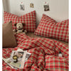 A red and green plaid duvet cover set displayed on a bed with pillows and magazines.