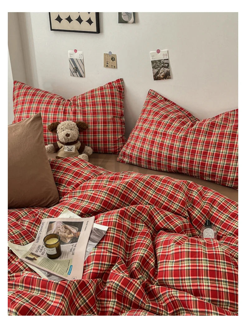 A red and green plaid duvet cover set displayed on a bed with pillows and magazines.