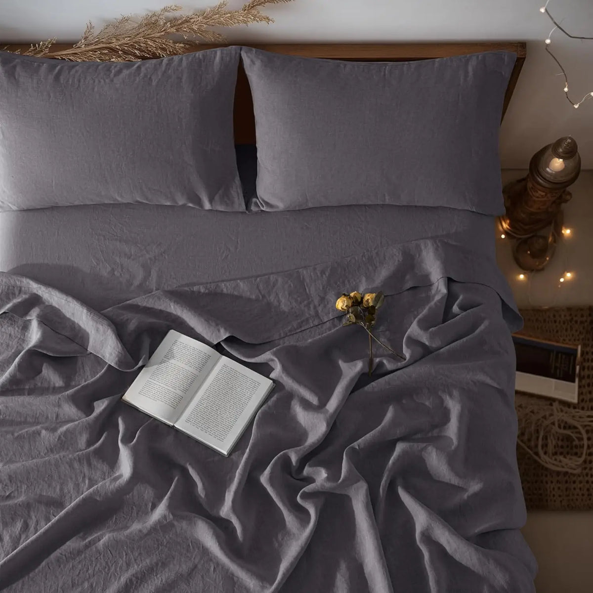 A gray linen bedding set featuring pillows, a duvet, and a throw draped on a bed.