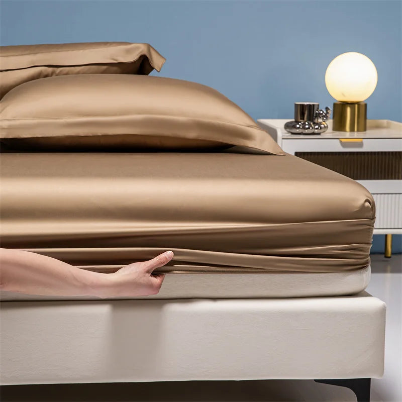 A hand touches a beige luxury bamboo bedding set on a bed against a light blue wall.