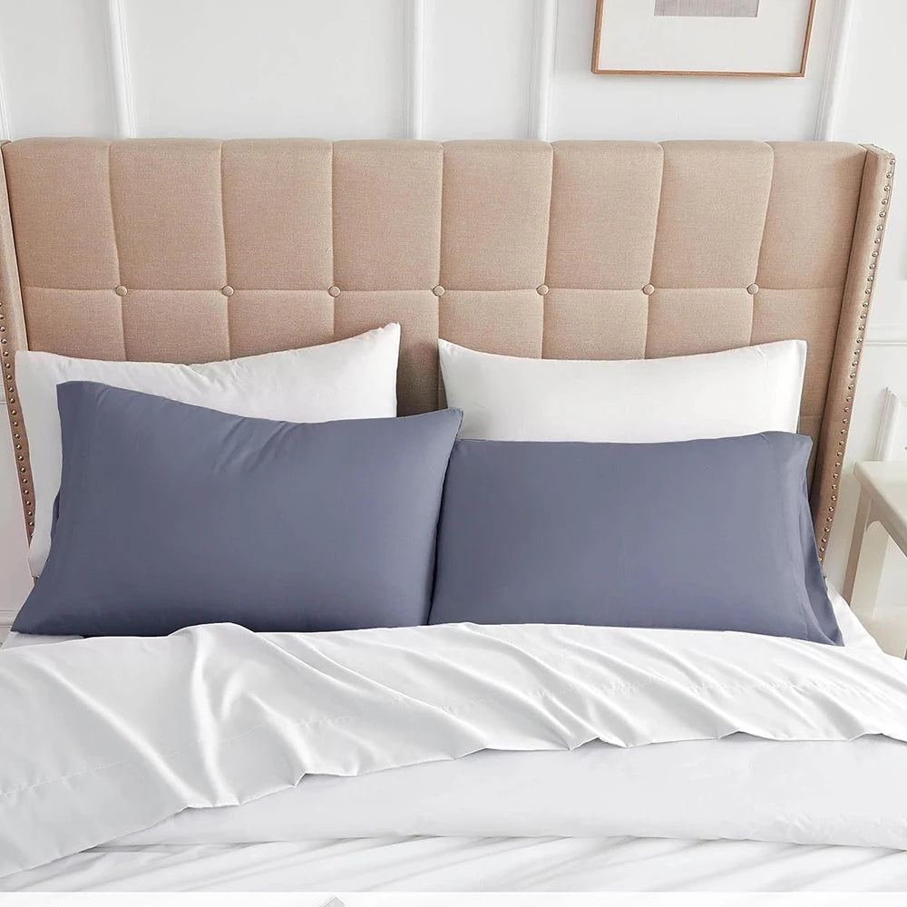 A bed with a padded headboard featuring beige upholstery and white and gray pillow covers.