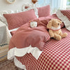 A plaid duvet cover set in red and white with lace embroidery, featuring a pink blanket and a teddy bear.