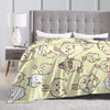 A beige flannel throw blanket featuring a pattern of cute Chiikawa cartoon characters on a bed.