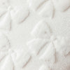 A close-up view of white faux fur pillow covers with a subtle diamond pattern on a textured fabric.