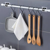 A silver curtain rod with hooks is mounted on a wall, holding various wooden kitchen utensils.