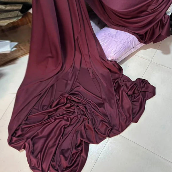 A deep maroon draping stretch fabric is shown in a flowing, gathered style on a light floor.