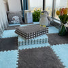 A soft plush EVA foam play mat with square tiles in gray and light blue on a floor.