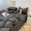 A dark gray duvet cover set with matching pillowcases and a decorative textile hanging on the wall.