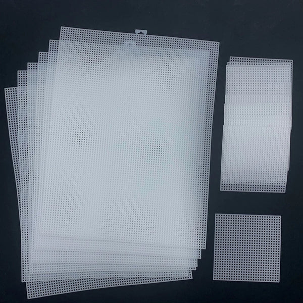A set of white hollow plastic grids used for cross stitching, displayed on a dark surface.