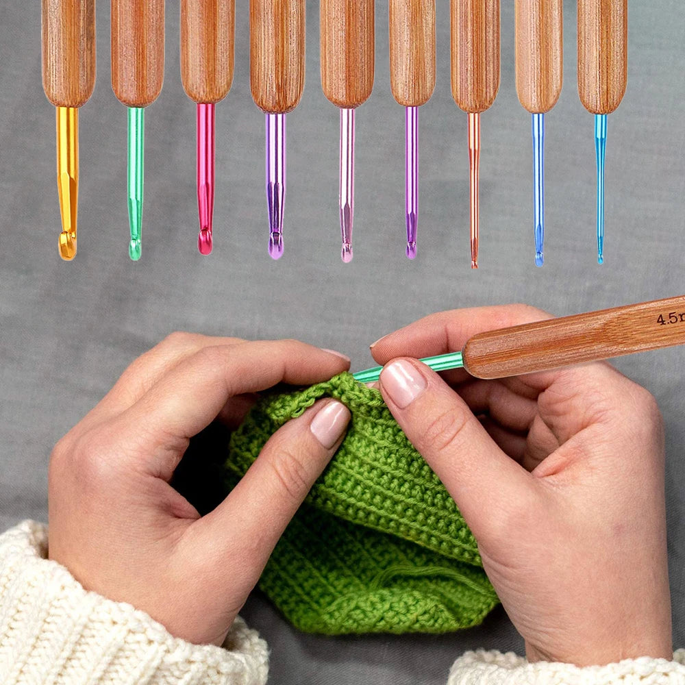 A hand is using a wooden knitting needle to insert a bamboo needle from a set into a green knitted fabric.