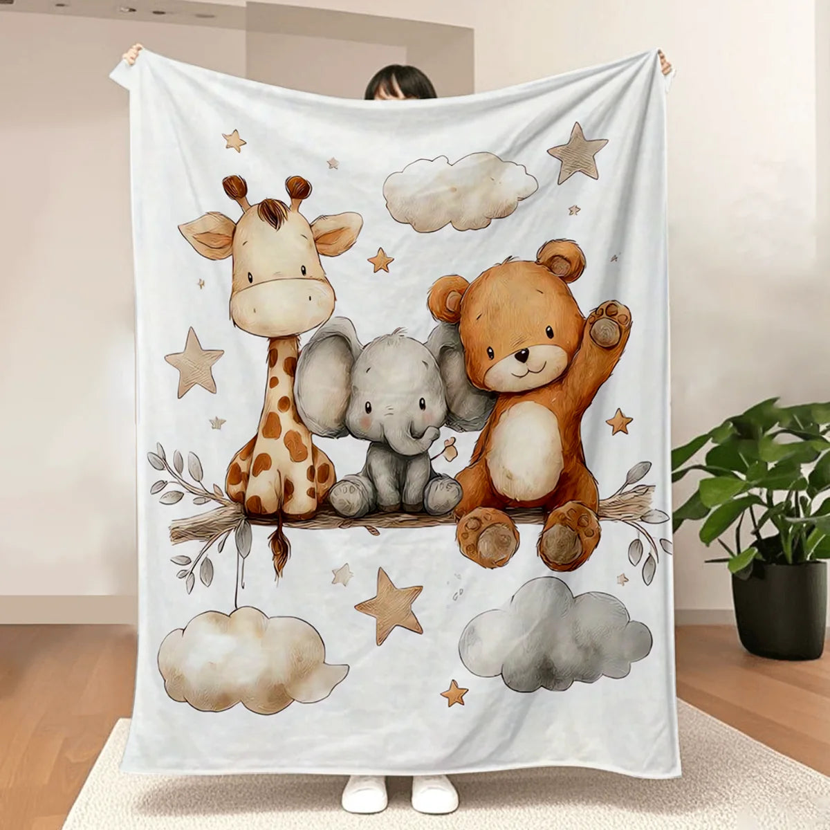 A white blanket featuring watercolor illustrations of a giraffe, an elephant, and a teddy bear sitting on branches with cloud