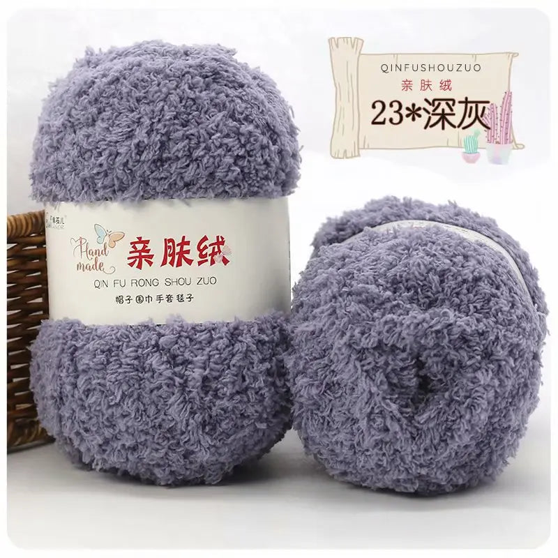A pair of fluffy purple coral velvet yarn balls for crafting displayed next to a label.