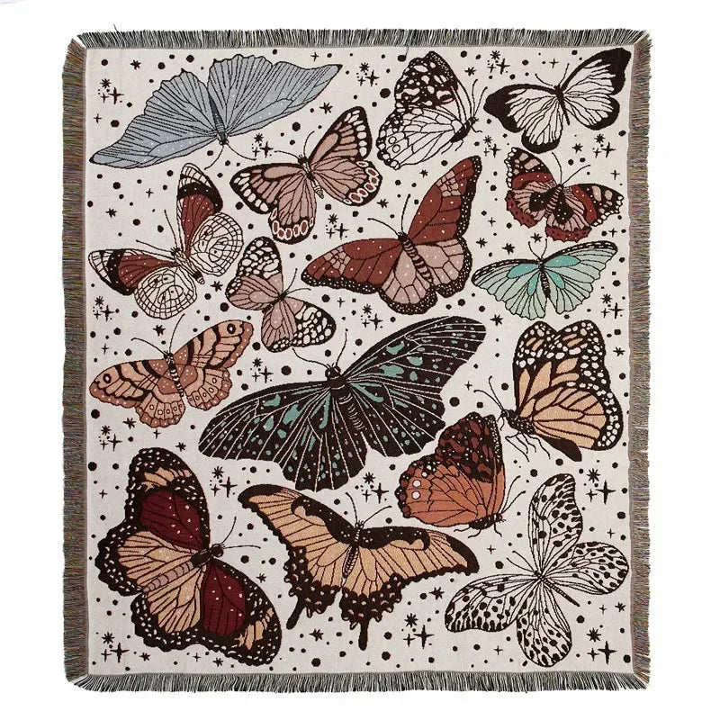 A throw blanket featuring a bohemian geometric pattern of various butterflies and floral elements on a neutral background.