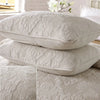 A set of light gray embroidered cotton quilted pillow covers stacked on a white surface.
