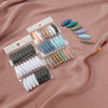 A collection of eight plastic safety pins in various shades of blue, green, and beige are displayed in small clear packaging.