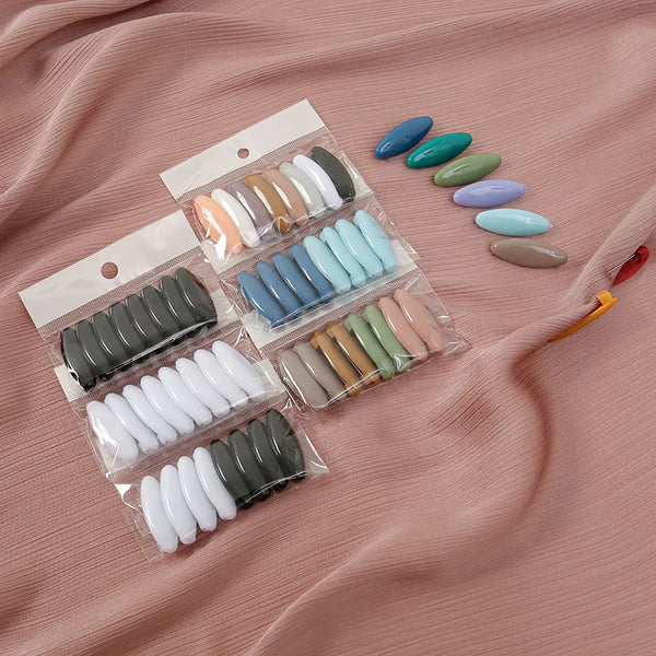 A collection of eight plastic safety pins in various shades of blue, green, and beige are displayed in small clear packaging.