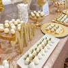 A table decorated with white and gold cupcakes, meringues, and a glitter tablecloth for a wedding or party.