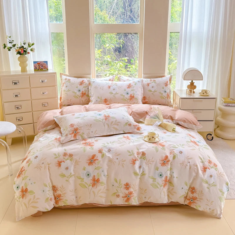 A light pink floral duvet cover and pillow set displayed on a bed with white wooden nightstands and sheer curtains.