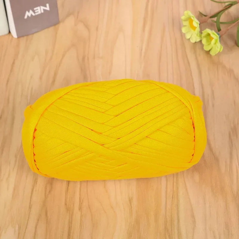 A bright yellow flat thread yarn ball lying on a wooden surface.