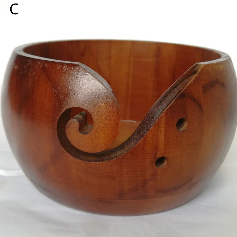 A wooden yarn bowl with a curved lip and a decorative swirl design.