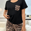 A woman models a black t-shirt with a leopard print pocket detail and matching leopard print shorts.