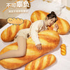 A soft plush yellow baguette shaped pillow is shown resting on white bedding.