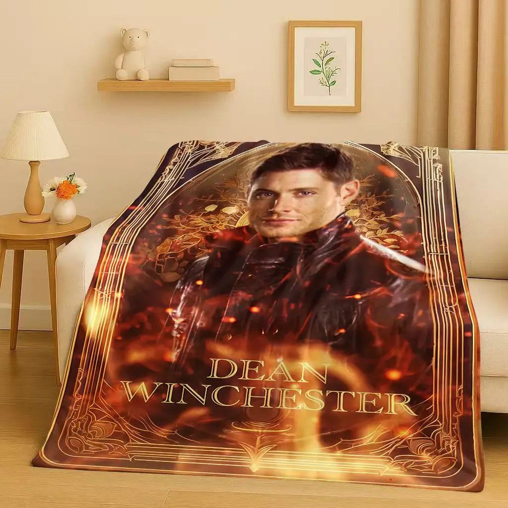 A large print featuring Dean Winchester with a fiery background and his name on an orange-toned flannel throw blanket.