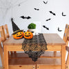 A wooden table set for Halloween featuring a black lace spider web table runner and a carved pumpkin decoration.