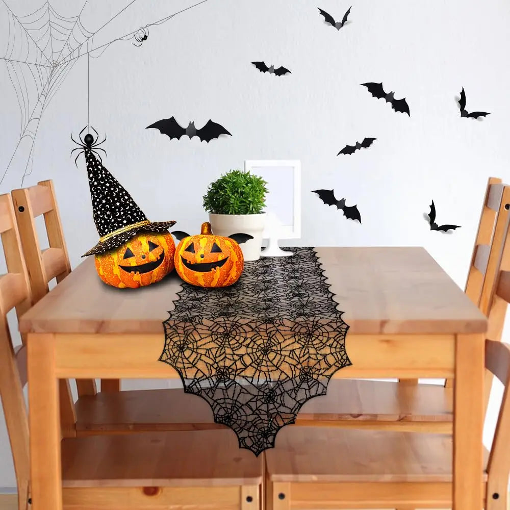 A wooden table set for Halloween featuring a black lace spider web table runner and a carved pumpkin decoration.