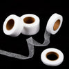 Rolls of white heavy duty iron-on hemming tape with loose strands unwinding