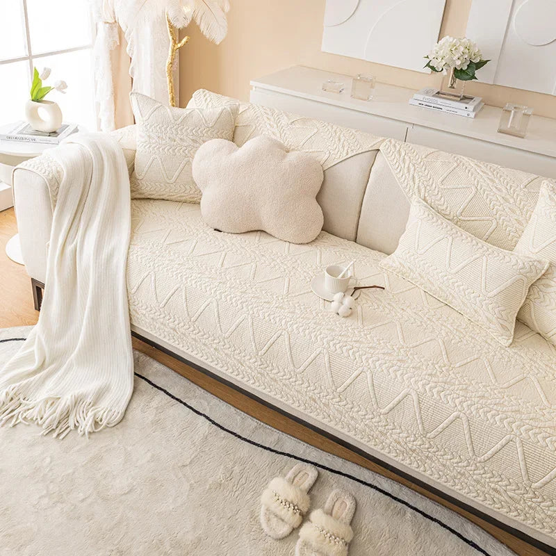 A cream woven sofa cover with a textured pattern displayed on a light-colored sofa.