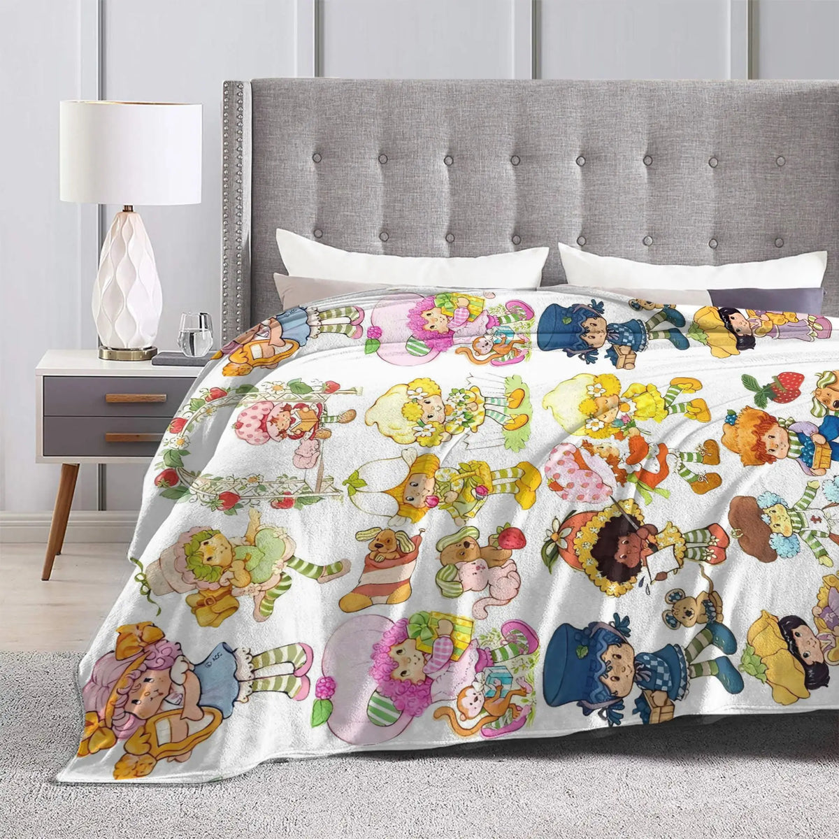 A colorful strawberry shortcake plush throw blanket featuring various sweet characters and fruit designs.