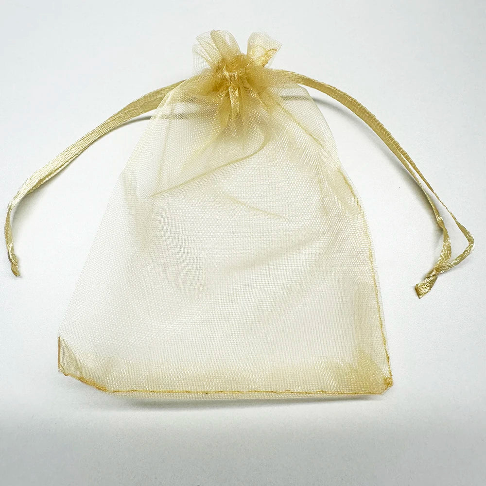 A sheer, light gold organza gift bag tied with a delicate ribbon, suitable for storing jewelry or candy.