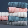 A stack of four rolled pure cotton face towels in shades of blue, pink, and white.