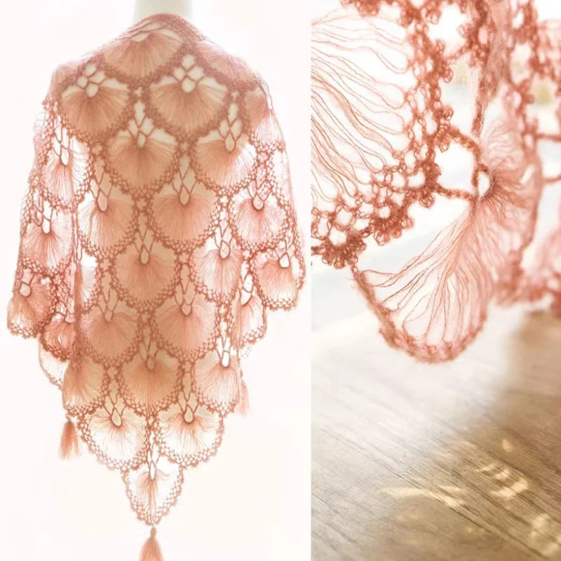 Close-up of a sheer, peach-colored lace fabric made from premium mohair yarn draped over a wooden surface.