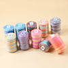 A collection of colorful bulk sewing thread spools in various shades and patterns arranged on a light background.