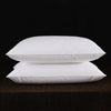 Two white natural goose down and feather sleeping pillows stacked on a dark surface.