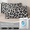 Two leopard print decorative pillow covers on a beige sofa next to a white washing machine.