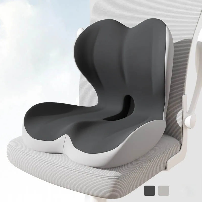 A gray ergonomic memory foam lumbar seat cushion is shown resting on a white chair seat.
