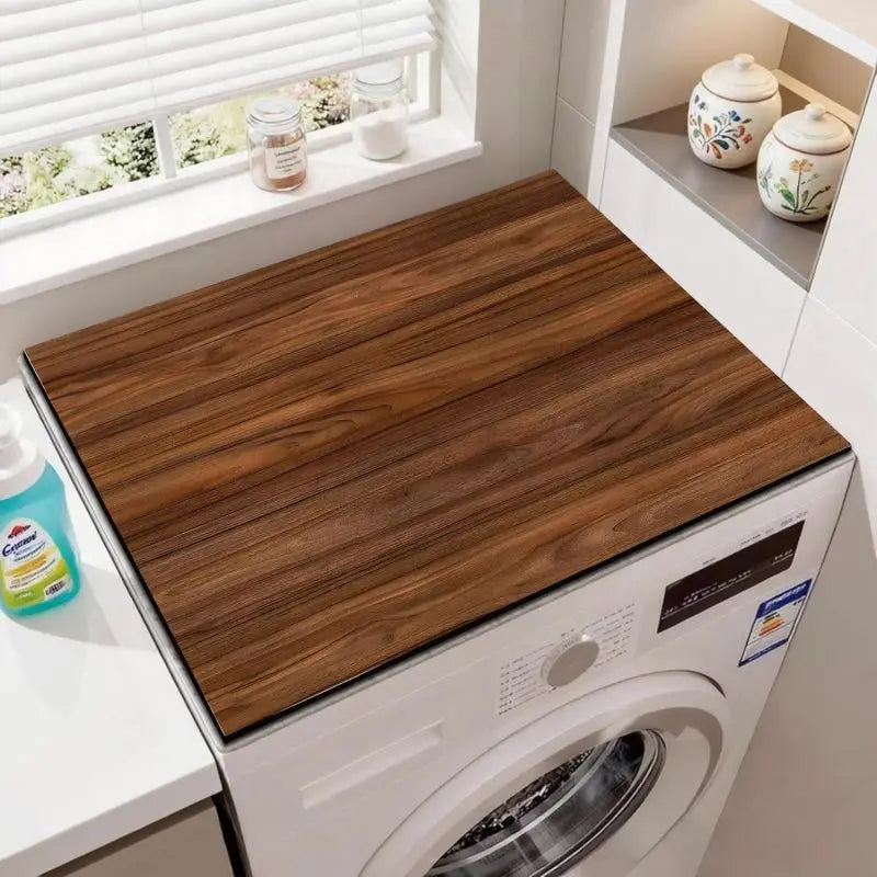 A brown wood grain fridge cover mat is placed on a white kitchen counter next to a white washing machine.