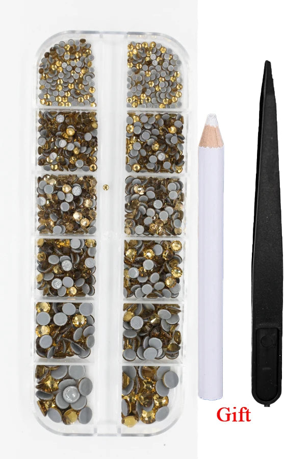 A clear plastic container holds various gold and silver crystal hot fix rhinestones and an applicator tool.