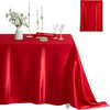 A red satin tablecloth set for elegant dining featuring candles, glassware, and a red drape.
