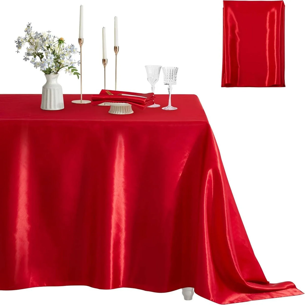 A red satin tablecloth set for elegant dining featuring candles, glassware, and a red drape.