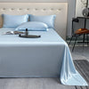 Light blue luxury bamboo flat sheets displayed on a bed with white pillows and a bedside table.