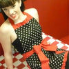 A woman wearing a black and white polka dot ruffle apron with red accents.