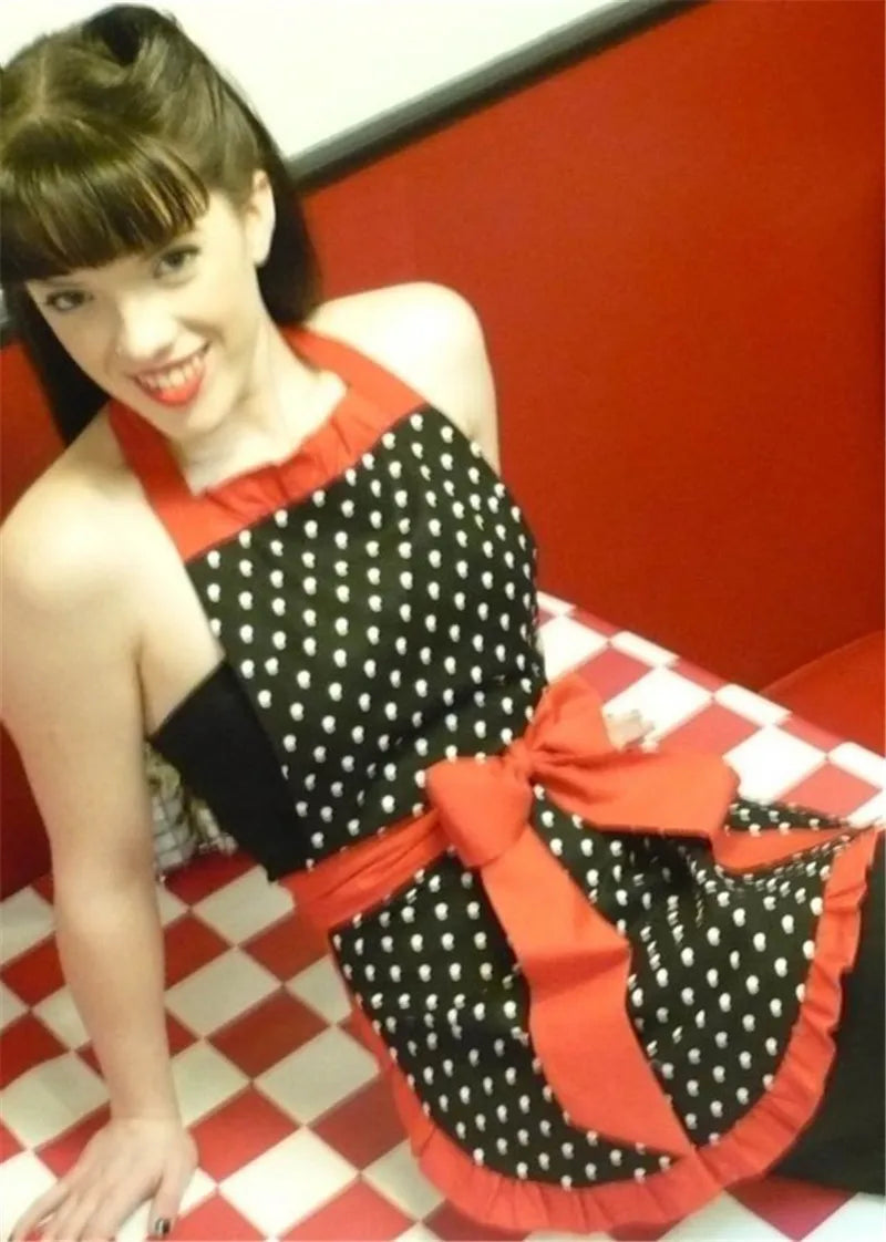 A woman wearing a black and white polka dot ruffle apron with red accents.