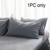 A single gray cotton pillowcase with an envelope closure is displayed on a bed.