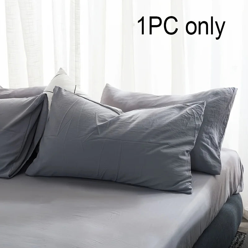A single gray cotton brushed pillowcase with an envelope closure on a bed.